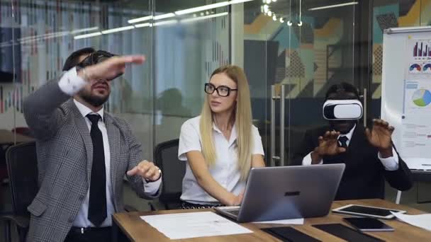Movimento lento de empresários multirraciais experientes que trabalham juntos na sala de reuniões usando computador e óculos de realidade aumentada — Vídeo de Stock