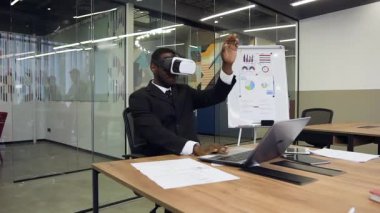Attractive portrait of focused young african american businesman in virtual reality headset which working in office room