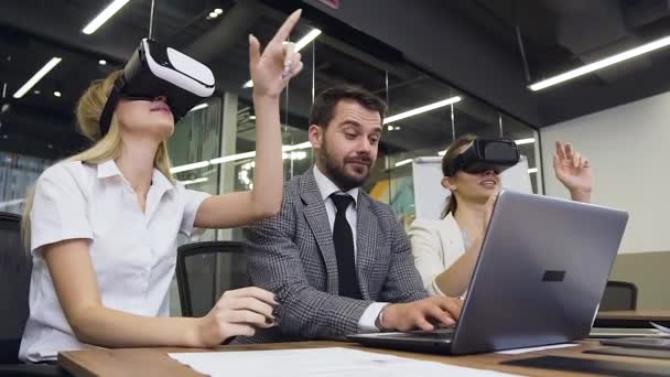 Business concept where high-skilled contented bearded business-mentor working at laptop while his pretty smiling corporate managers trying special 3d glasses — Stock videók