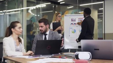 Good-looking high-skilled mixed race 30-35s business people working under joint project in boardroom