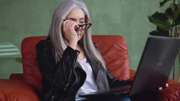 Slow motion of good-looking satisfied modern stylish lady in glasses which working on laptop at home — 비디오