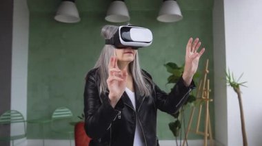 Beautiful balanced senior gray haired lady in trendy jacket in special 3d glasses working on imaginary screen