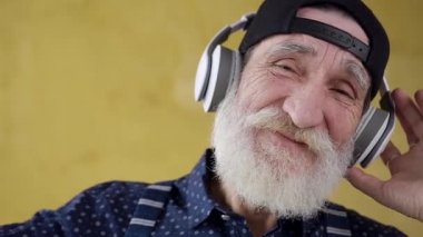 Close up of joyful satisfied bearded stylish man in headphones which listening modern songs