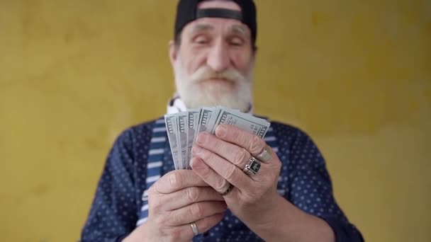 Front view of attractive smiling rich stylish bearded old man which holding in his hands dollars banknotes — Stockvideo