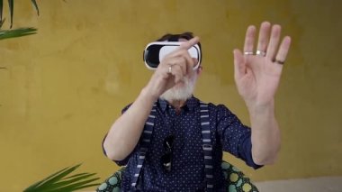 Handsome focused respected stylish mature man with gray beard making calculating actions on virtual screen wearing special 3d goggles