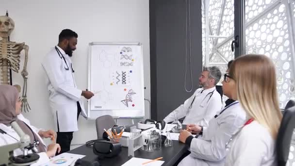 Group of young doctors of mixed race medical listens to a lecture by an experienced African American doctor at a hospital conference room — Stockvideo