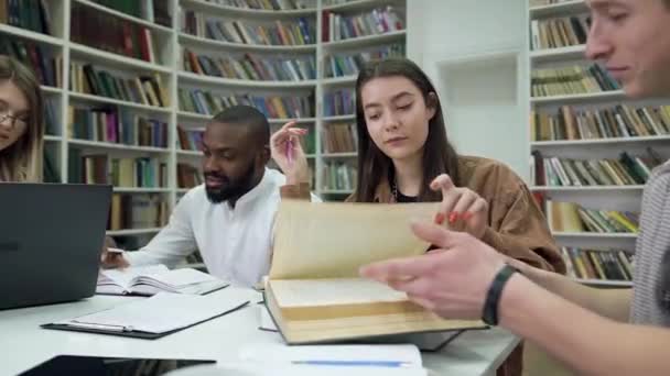 Close up de sorrindo atraentes modernos estudantes de raça mista que se preparam para os exames na biblioteca — Vídeo de Stock