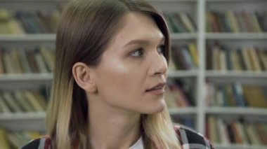 Close up of attractive satisfied modern young woman which looking at camera, being in the library