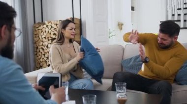 Kızgın genç kadın yastıkla dövüyor korkunç sakallı kocasını ve profesyonel psikoloğa yaptıkları ortak ziyarette ağlıyor.