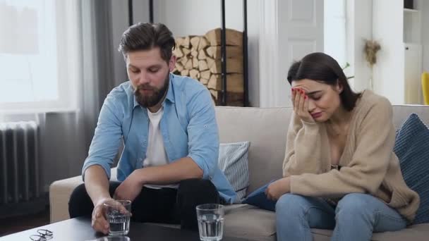 Нещасна молода жінка слухає свого збудженого бородатого чоловіка, який розповідає про проблеми в їх спільному житті під час прийому в психолога — стокове відео