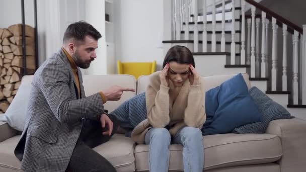 Привлекательный недовольный бородатый мужчина спорит со своей молчаливой разочаровывающей девушкой на диване — стоковое видео