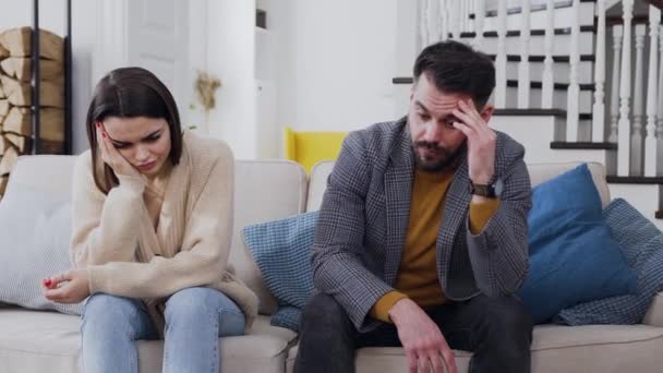 Вид разочаровывающей усталой в семейных отношениях молодой супружеской пары, сидящей на диване во время визита к психологу — стоковое видео