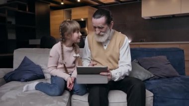Gülümseyen mutlu, 12 yaşında güzel bir kız. Saygıdeğer büyük babasıyla kanepede oturuyor ve i-pad 'de bir şeyler karıştırıyor.