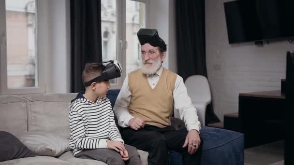 Dobrze wyglądające pozytywne dwa różne pokolenia ludzi jako dziadek i wnuk grający w gry wideo przy użyciu gogli wirtualnej rzeczywistości — Wideo stockowe