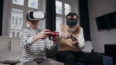 Güzel görünümlü sakallı bir adam ve genç bir çocuğun sanal gerçeklik kulaklığıyla oyun kağıtlarını kullanarak birlikte oynamalarının ön görüntüsü.