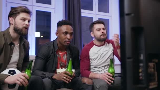 Gros plan de jeunes hommes sympathiques excités qui célèbrent le ballon marqué pendant le match de football à la télévision à la maison et boire de la bière — Video
