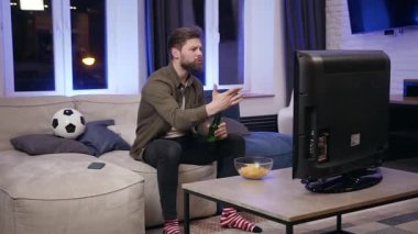 Side view of emotional attractive fierce football fan which sitting near the tv and cheerfing his favourite team to play better