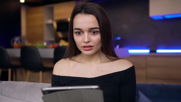 Vorderseite der attraktiven überrascht junge moderne Mädchen, die ihre Hände aus gesehen gute Nachrichten auf Tablet-PC-Bildschirm gehoben — Stockvideo