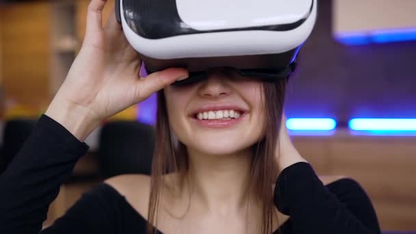 Apelando positivo sorrindo jovem morena vestindo fone de ouvido realidade virtual e mãos em movimento na tela imaginária estar em casa — Vídeo de Stock