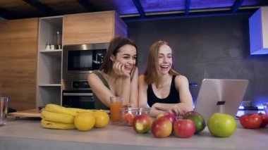 Gülümseyen, mutlu, ince, tatlı esmer ve sarışının yakın çekimde dizüstü bilgisayar ekranına bakıp komik fotoğraflardan gülmelerini istiyorum.