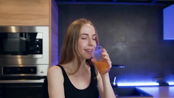 Gutmütige positive glückliche Blondine, die frischen Fruchtsaft genießt und mit aufrichtigem Lächeln in die Kamera blickt — Stockvideo