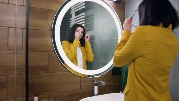 Närbild av sympatisk snygg ung affärskvinna i oliv kostym som tittar in i spegeln och sätta på glasögon innan hennes avgång för arbete — Stockvideo