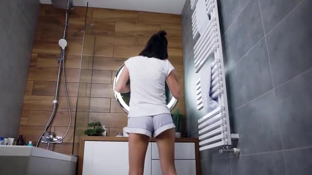 Glücklich zufrieden junge Brünette tanzt im Badezimmer, während sie ihre Zähne putzt — Stockvideo