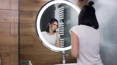 Dişlerini fırçalarken banyo aynası önünde dans eden genç, siyah saçlı kadının yavaş çekim gücü.