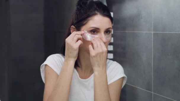 Detailní záběr okouzlující 30-35-leté brunetky, která aplikuje náplasti pro hladkou kůži pod očima — Stock video