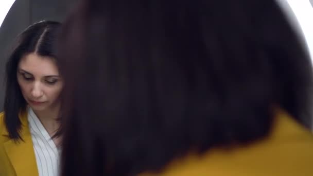 Стильная современная самоуверенная красивая женщина в оливковой куртке, глядя на свое отражение в зеркале и надевая маску для защиты от Ковид-19 — стоковое видео