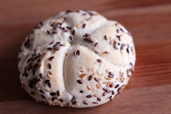 Leckerer frisch gebackener Butterkaiser mit Leinsamen und Sonnenblumenkernen. Draufsicht, Kopierraum, selektiver Fokus. Gebäck auf einem Holztisch. verschwommener Hintergrund. — Stockfoto