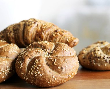 Lezzetli tereyağı kaiser rulo ile keten tohumu ve ayçiçeği tohumu fırından yeni çıkmış. Üstten Görünüm, kopya alanı, seçici odak. Ahşap bir masa üzerinde hamur işleri. Arka plan bulanık. Taze pasta kavramı.