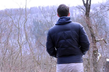 Genç ayakta kışın nehir kıyısında adam. İnsanlar, sezon ve boş zaman etkinlikleri.