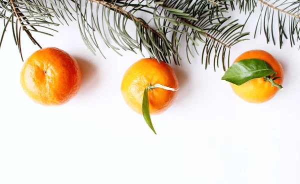 Marco de Navidad. Mandarinas orgánicas frescas crudas con ramas de árbol, aisladas sobre fondo de mesa blanco. Decoración de invierno. Puesta plana, superior . —  Fotos de Stock