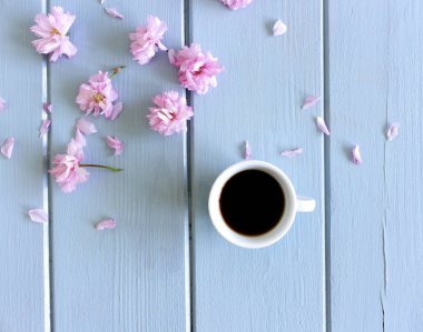 Çiçekli Sakura dalları, ahşap arka planda siyah kahveli beyaz fincan. Düz konum, üst görünüm, metin için yer.