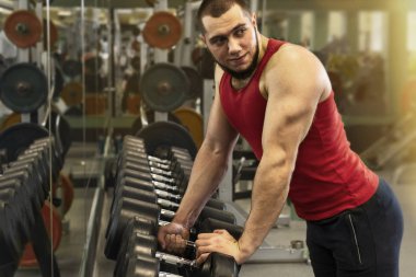 Spor salonunda çalışan adam. Güçlü adam eğitim için dambıl alır..