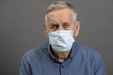 Tıbbi koruyucu maskeli yaşlı bir adamın portresi. Yaşlılar için koronavirüs tehlikesi kavramı