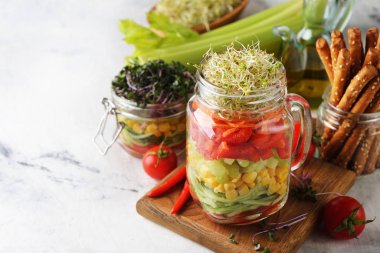 Beyaz arka planda bir kavanozda mikro yeşillikle vegan salatası.