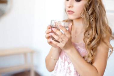 Dişi eller temiz bir bardak su tutuyor. Arka planda sümük var. Sağlıklı yaşam tarzı.