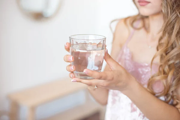 Female hands holding a clear glass of water. Slime body on background. Healthy lifestyle. — Stock Photo, Image