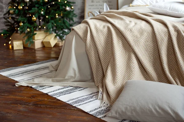 Arredo appartamento di Natale, scandinavo accogliente arredamento domestico, letto con calde coperte a maglia accanto all'albero di Natale. Luci e ghirlande . — Foto Stock