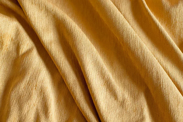 Mustard crumpled material for background or texture, tablecloth on a wooden table — Stock Photo, Image