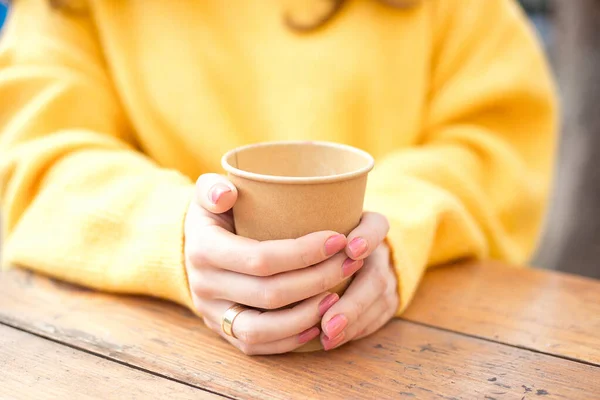 Mädchen halten in einem Café auf der Straße eine Tasse heißen Kaffee in der Hand — Stockfoto