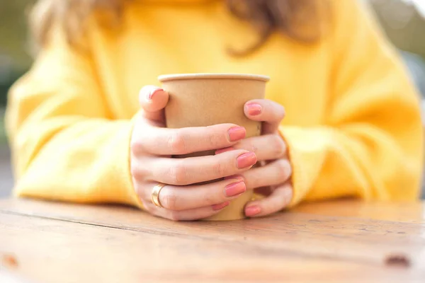 Mädchen halten in einem Café auf der Straße eine Tasse heißen Kaffee in der Hand — Stockfoto