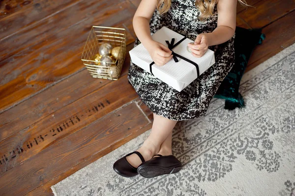 Primo piano della mano femminile che tiene una scatola regalo rossa avvolta e decorata con fiocco bianco, nastro. Piccolo regalo nelle mani della bambina presente per Natale, San Valentino, Capodanno, compleanno . — Foto Stock