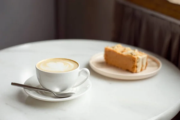 Rebanada de pastel de caramelo y un tenedor en el lado derecho. Una taza de café caliente con tierra en el fondo.Primer plano . — Foto de Stock