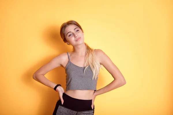 Mujer caucásica joven usando en sujetador deportivo sobre fondo aislado sonriendo con las manos en las caderas con los ojos cerrados y gesto en la cara soñando con la felicidad — Foto de Stock