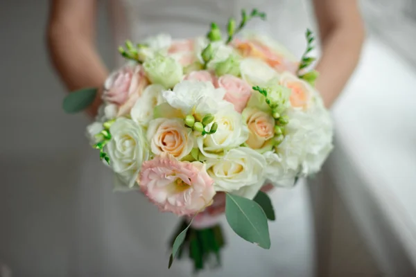 Gros plan marié dans un costume et la mariée dans une robe blanche sont debout et tenant un bouquet de roses pêche, eustomes et fleurs et de verdure — Photo