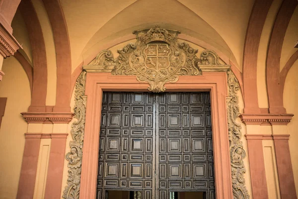 Royal design op een houten deur op een oker muur in Sevilla, Spanje, Europa — Stockfoto
