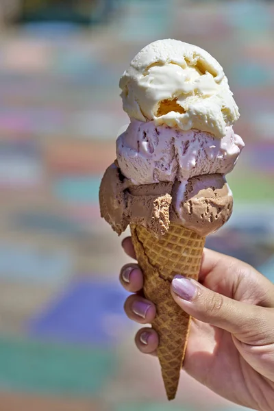 Summertime enjoyment: Female hand holding three scoop ice cream waffle cone — Stock Photo, Image